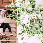 Home PEMF Units: Advantages of Having a PEMF Machine for Personal Use A woman sitting on a wooden staircase with a laptop, working diligently on her tasks.