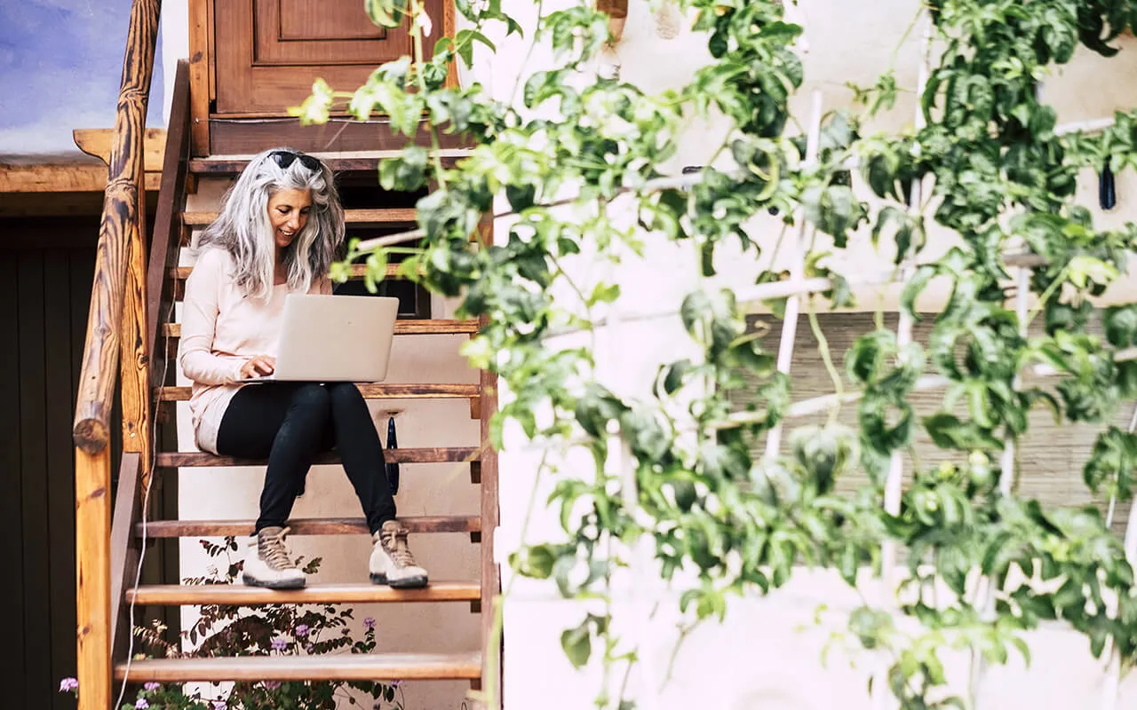 We Love Pulse PEMF: Running An Animal Wellness Business A woman sitting on a wooden staircase with a laptop, working diligently on her tasks.