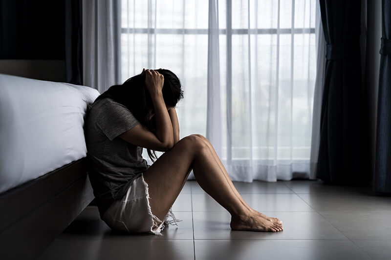 Restoring Balance with Craniosacral Therapy A woman sitting on the floor in front of a bed.