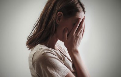 A woman hiding her face with her hands, possibly expressing embarrassment, sadness, or frustration.
