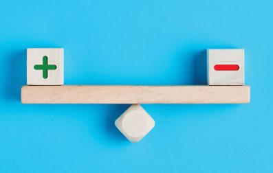 Wooden balance with positive sign and negative sign blocks.